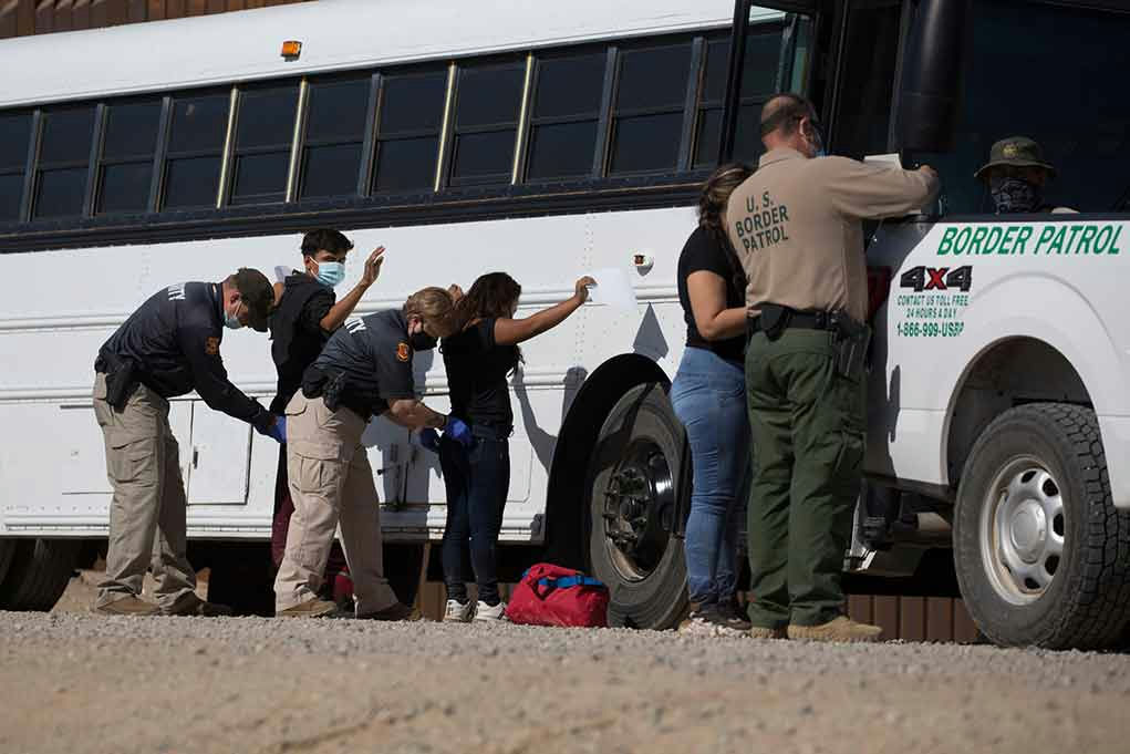 Border patrol officers investigating people near a bus