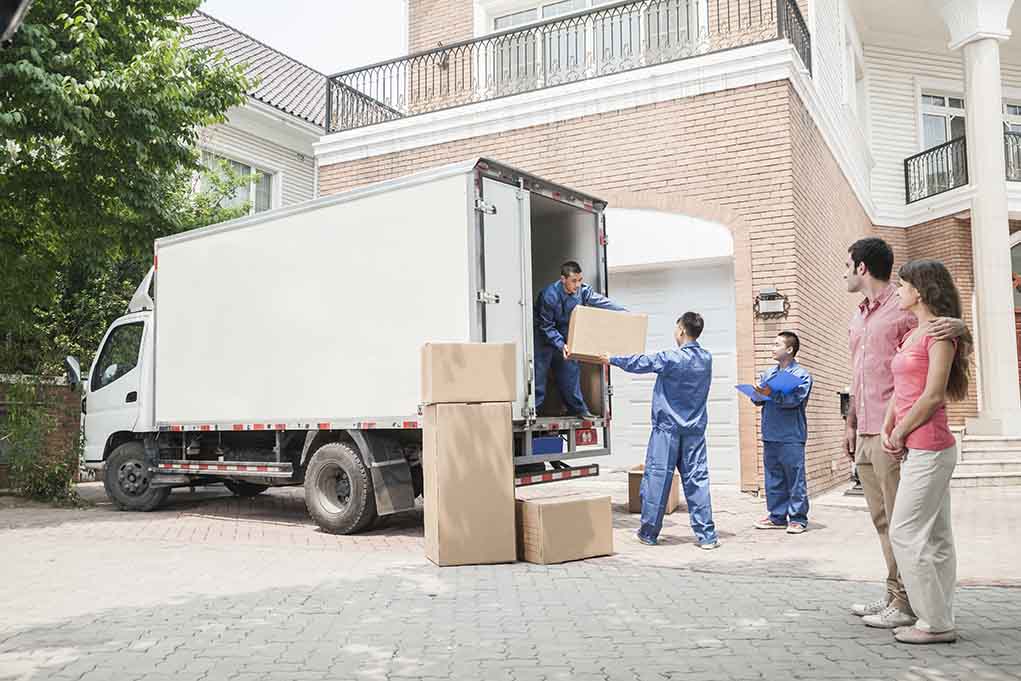 Workers unloading boxes from a moving truck in a residential driveway